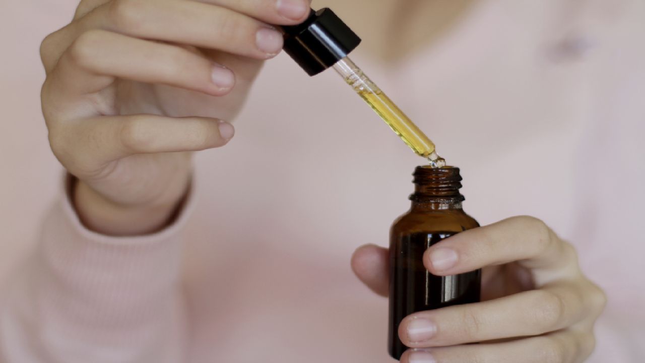 Unidentified person holds bottle and pipetted of jojoba oil