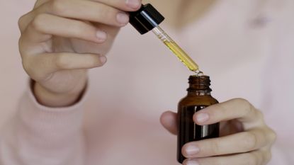 Unidentified person holds bottle and pipette of jojoba oil