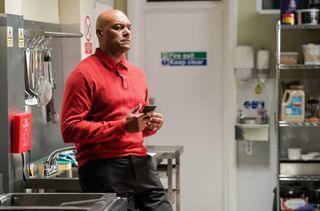 George Knight in the Queen Vic kitchen looking at his mobile phone