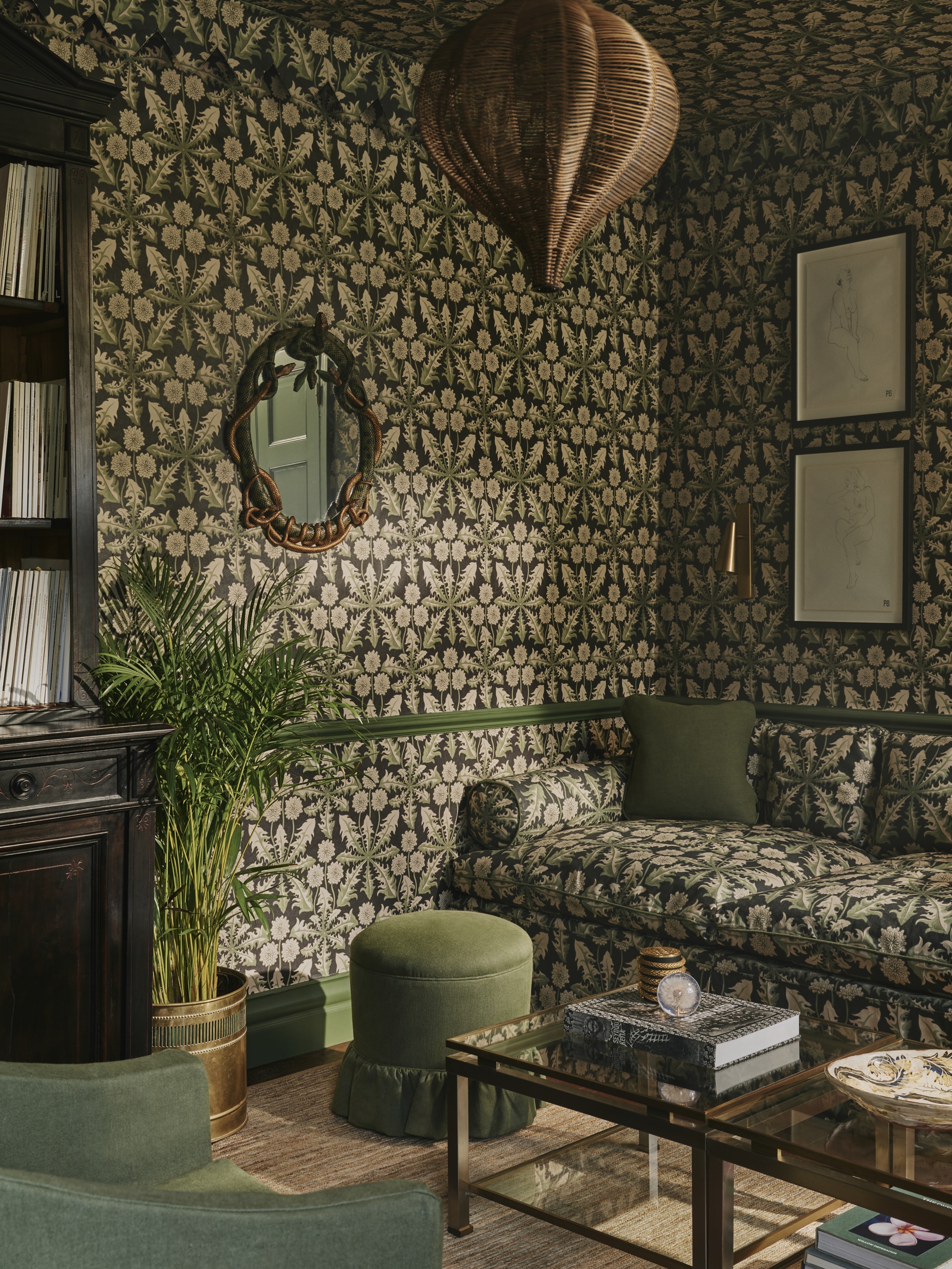 a living room with pattern drenched wallpaper and sofa with a green thistle pattern, green furniture and paint details
