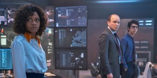 Ms. Moneypenny, Bill Tanner and Q stand in front of a bank of large monitors in 'No Time To Die'