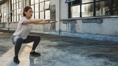 woman doing bodyweight exercises in empty room 