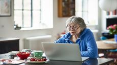 An older female retiree looks at a computer.