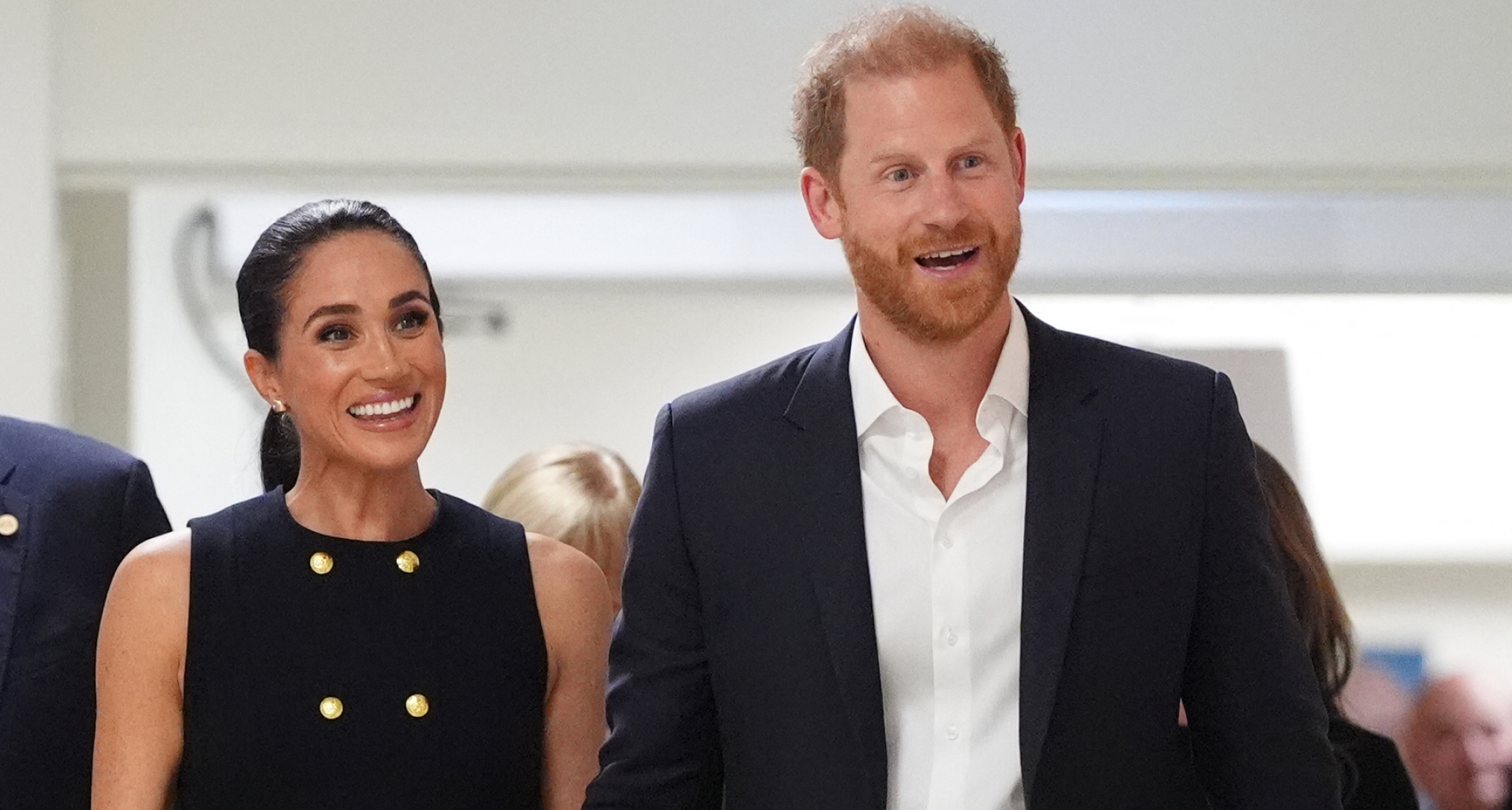 Prince Harry and Meghan Markle smiling walking next to each other