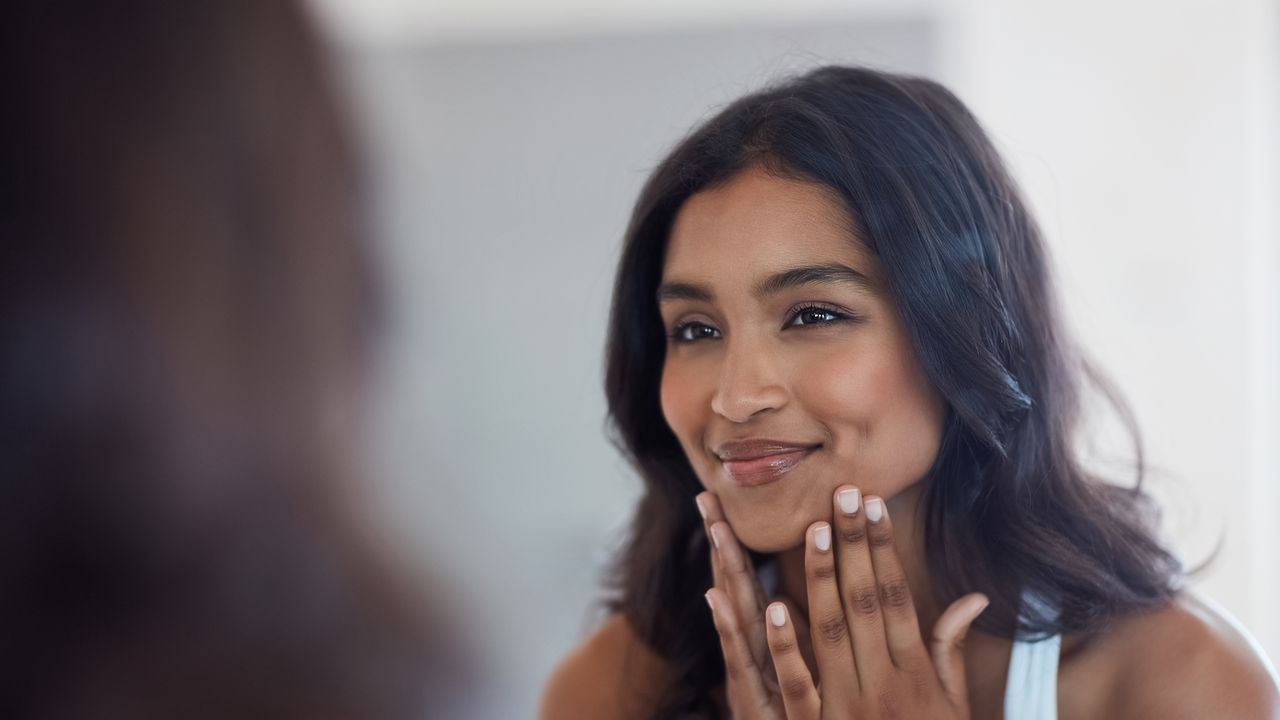 woman applying skincare in mirror