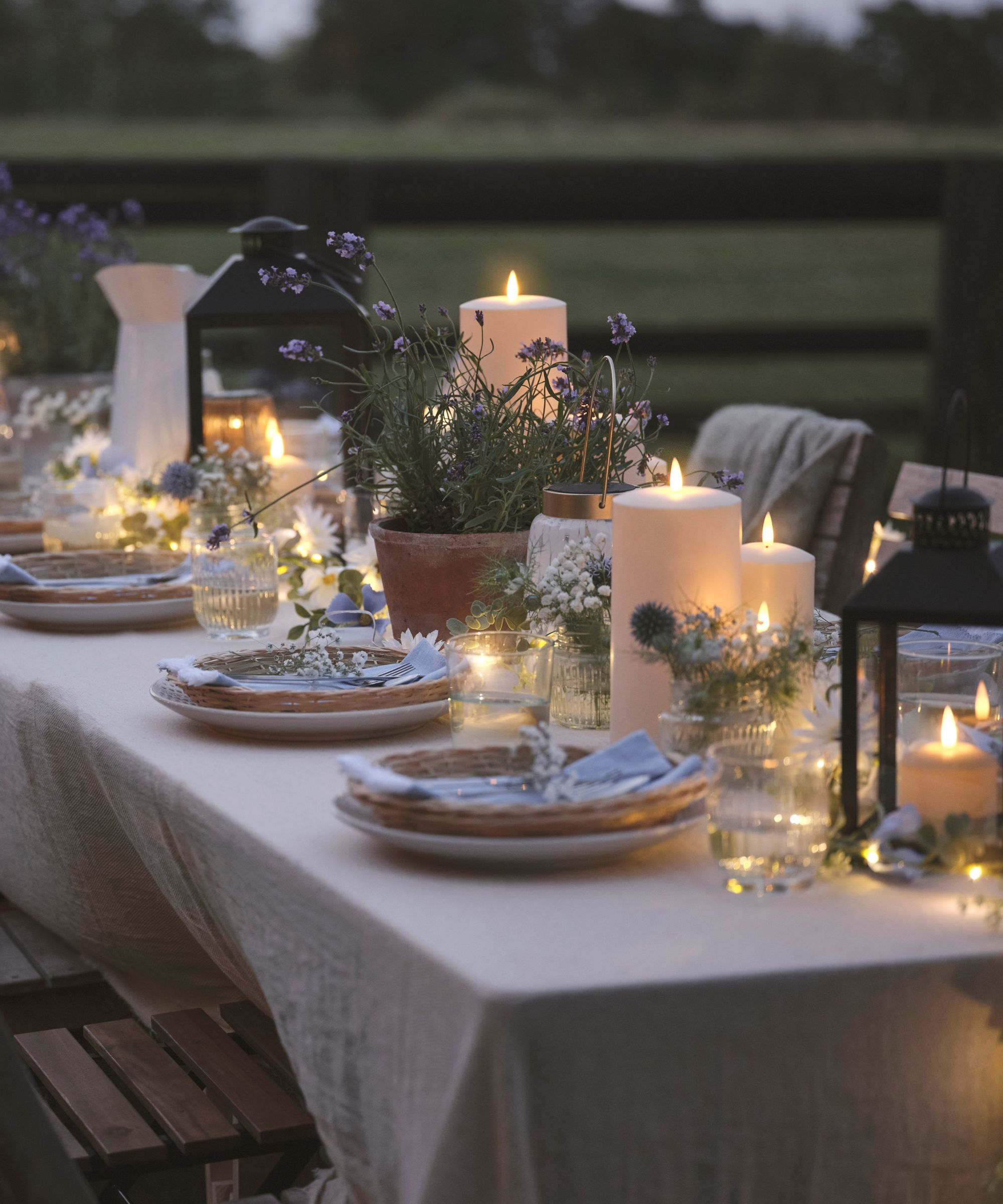 Outdoor table with plates, flowers, candles and lanterns