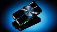 Kodak EasyShare V610: Sleek black Kodak camera with dual lens feature on a reflective surface and blue background