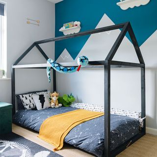 boys bedroom with mountain wall mural and house shaped bed