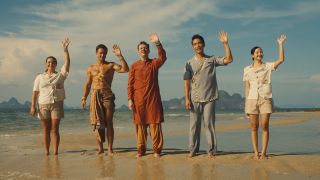 The staff of The White Lotus in Thailand (including Dom Hetrakul as Pornchai and Lalisa Manobal as Mook, far right) stand on the beach to great their latest guests in The White Lotus Season 3.