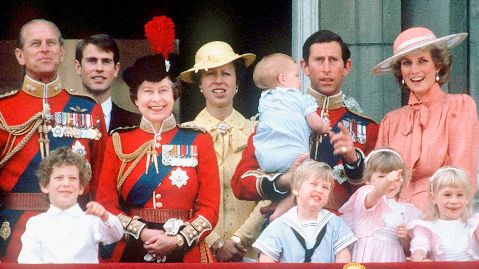 Princess Diana wears a peach outfit and is seen laughing along with Queen Elizabeth II and other members of the Royal Family on the balcony at Buckingham Palace in June, 1985