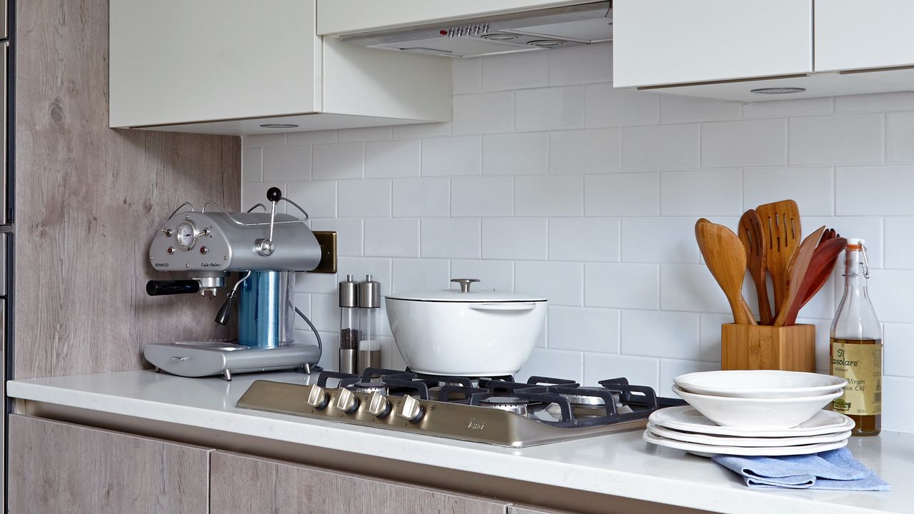 A white-tiled kitchen with wood-effect cupboards and a silver coffee machine