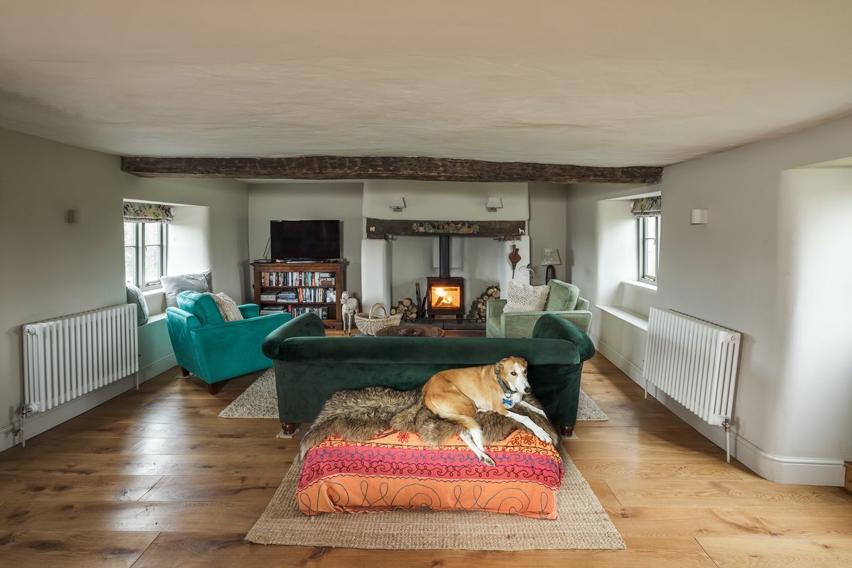 The living room is located within the original section of the house. A new woodburner within the original inglenook heats the space, along with column radiators.
