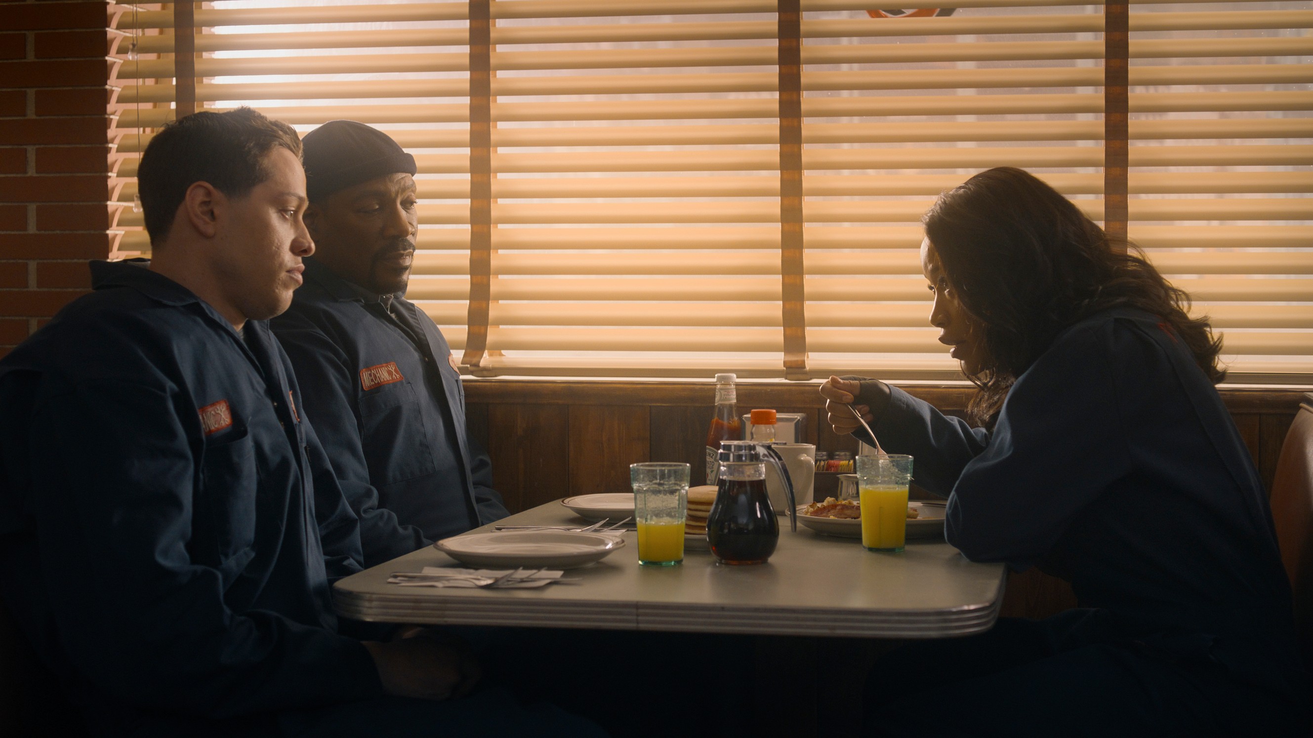L-R: Travis (Pete Davidson), Russell (Eddie Murphy) and Zoe (Keke Palmer) sitting together at a diner table in a scene from Prime Video's "The Pickup"