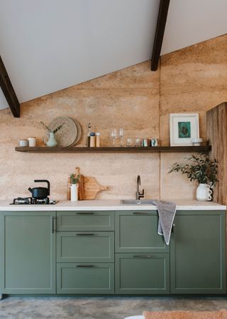 Green kitchen cabinets with open shelving above the sink