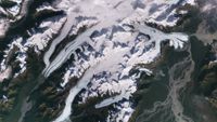 A satellite image of white streaks on top of greenish land.