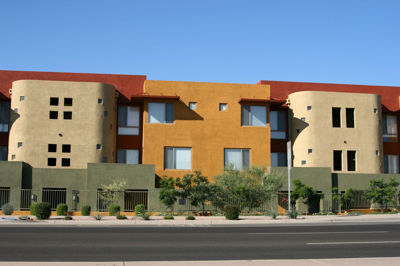 red, orange, and tan apartment building with plants out front