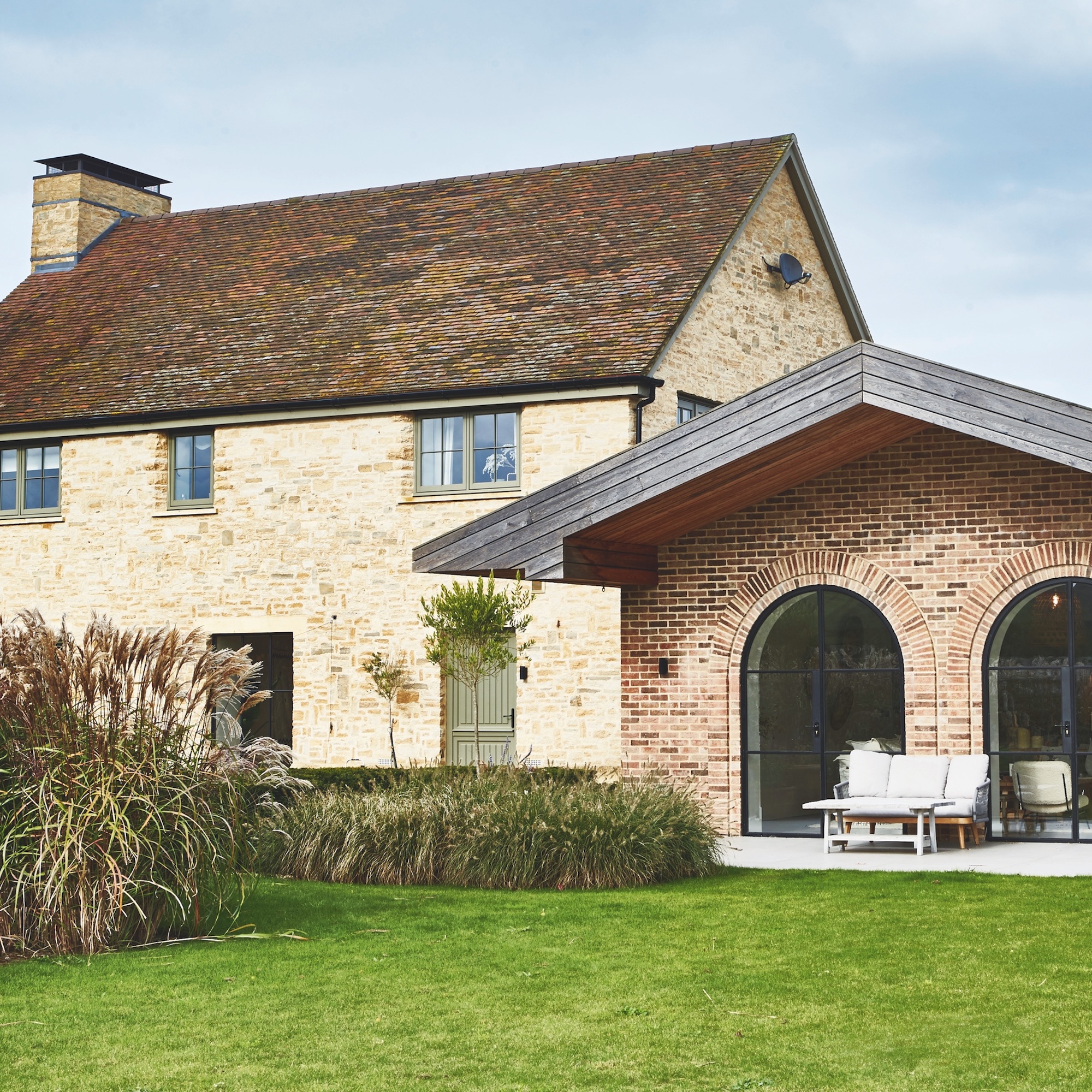 modern stone farmhouse with contemporary brick extension with arched patio doors