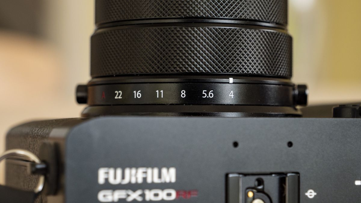 All-black Fujifilm GFX100RF rangefinder-style camera on a wooden table