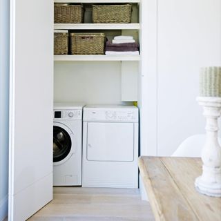 white walls with wooden flooring basket and washing machine