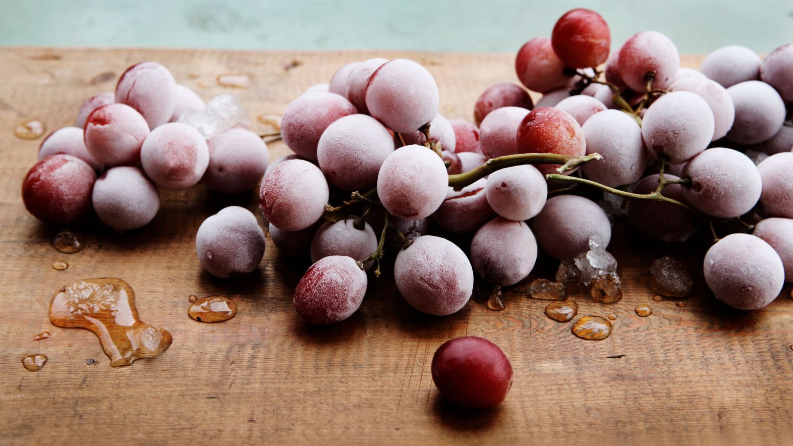 Bunch of frozen red grapes on a wooden board