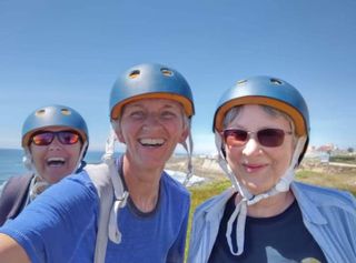 Three women wearing cycling helmets on a group tour for solo travellers