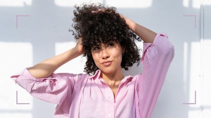A woman touching her curly hair to demonstrate how often should you cut your hair