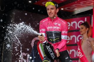 Simon Yates sprays another bottle of champagne on the podium