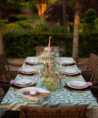 An outdoor dining table with a green and white tablecloth