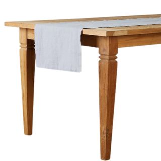 The end of wooden vintage dining table with a light gray linen table runner on top of it