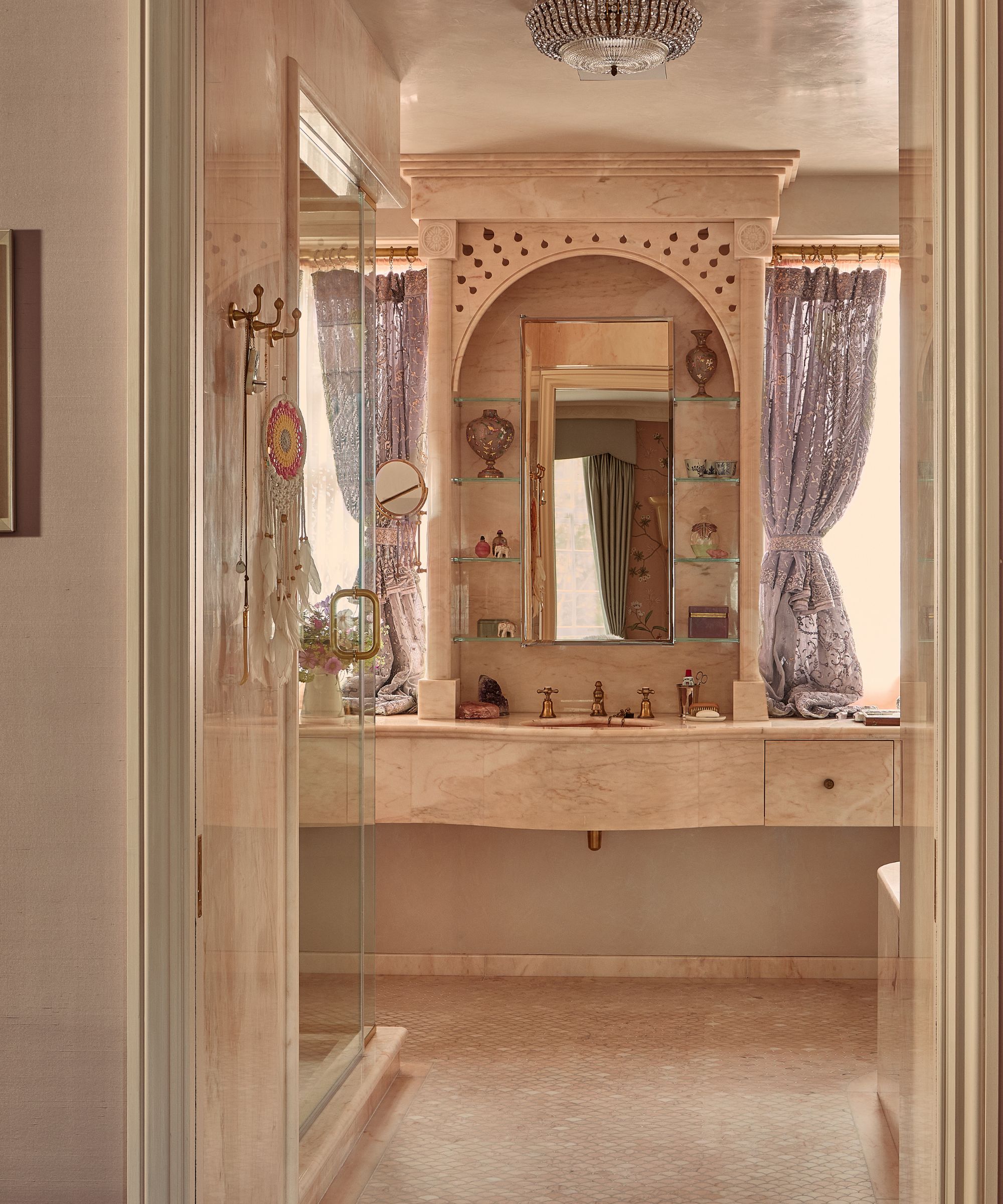 Pink marble vanity unit with arched alcove, sink with gold taps and purple curtains