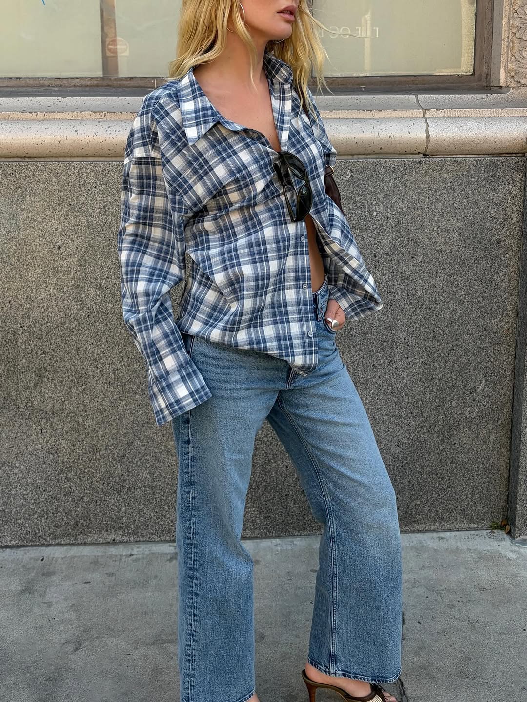 Image of a woman wearing jeans and plaid button-down shirt, best summer denim outfit inspiration 2026.