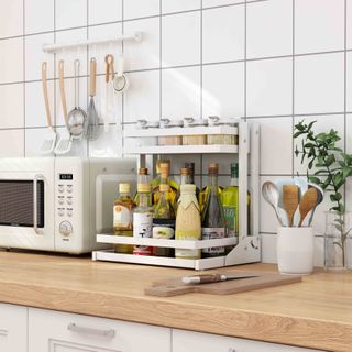 kitchen storage, spice rack on countertop, white wall tiles, utensil pot, microwave, hanging utensils