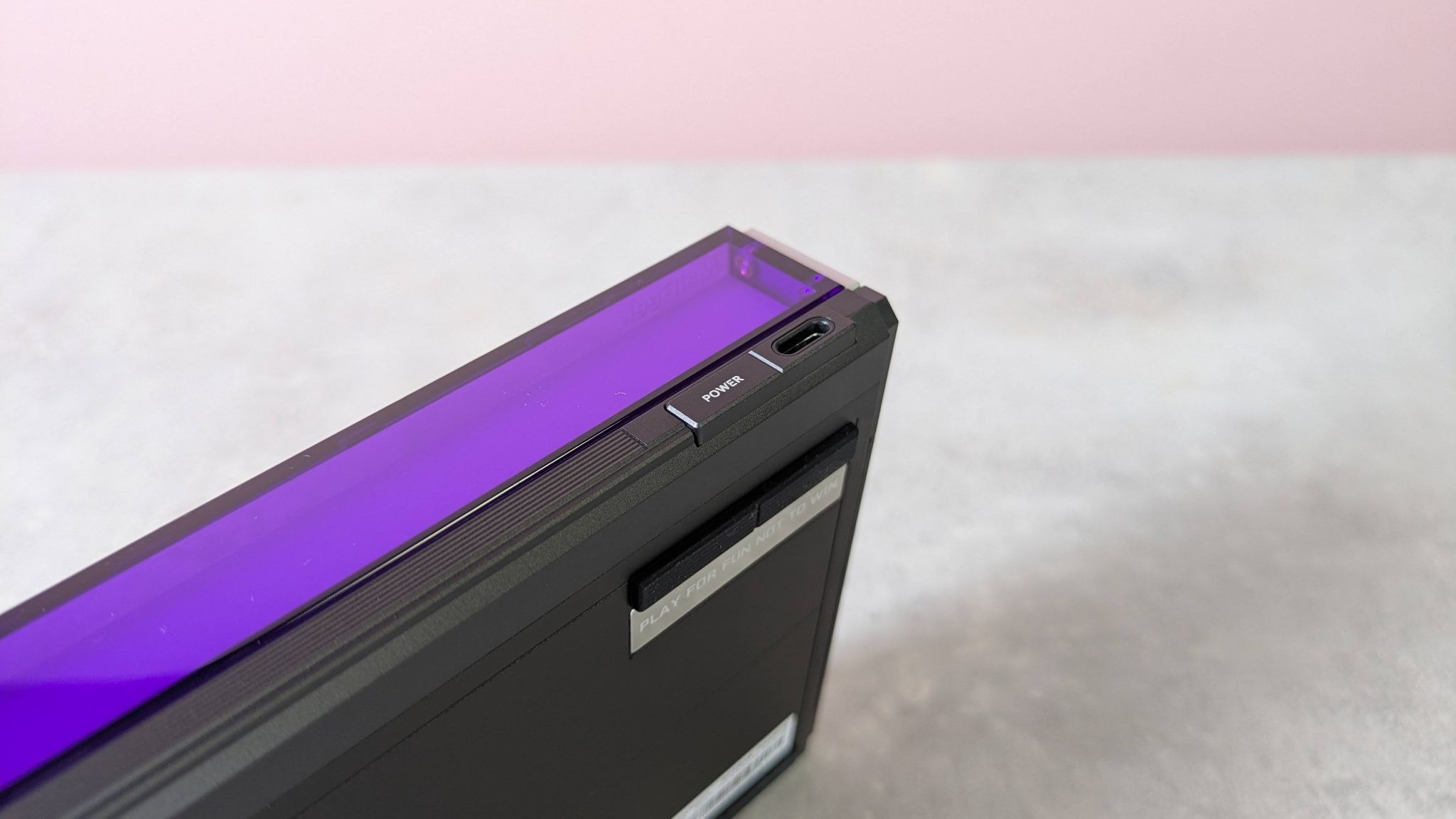 Close-up of power button and USB-C port of MelGeek Made68 Ultra V2, on desk with pink wall in background