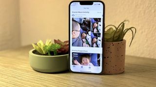 An iPhone leaning against a plant pot while displaying a Family Sharing album