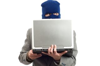 masked criminal behind laptop