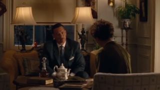 Tom Hanks sitting in a suit, having tea and a conversation in Saving Mr. Banks