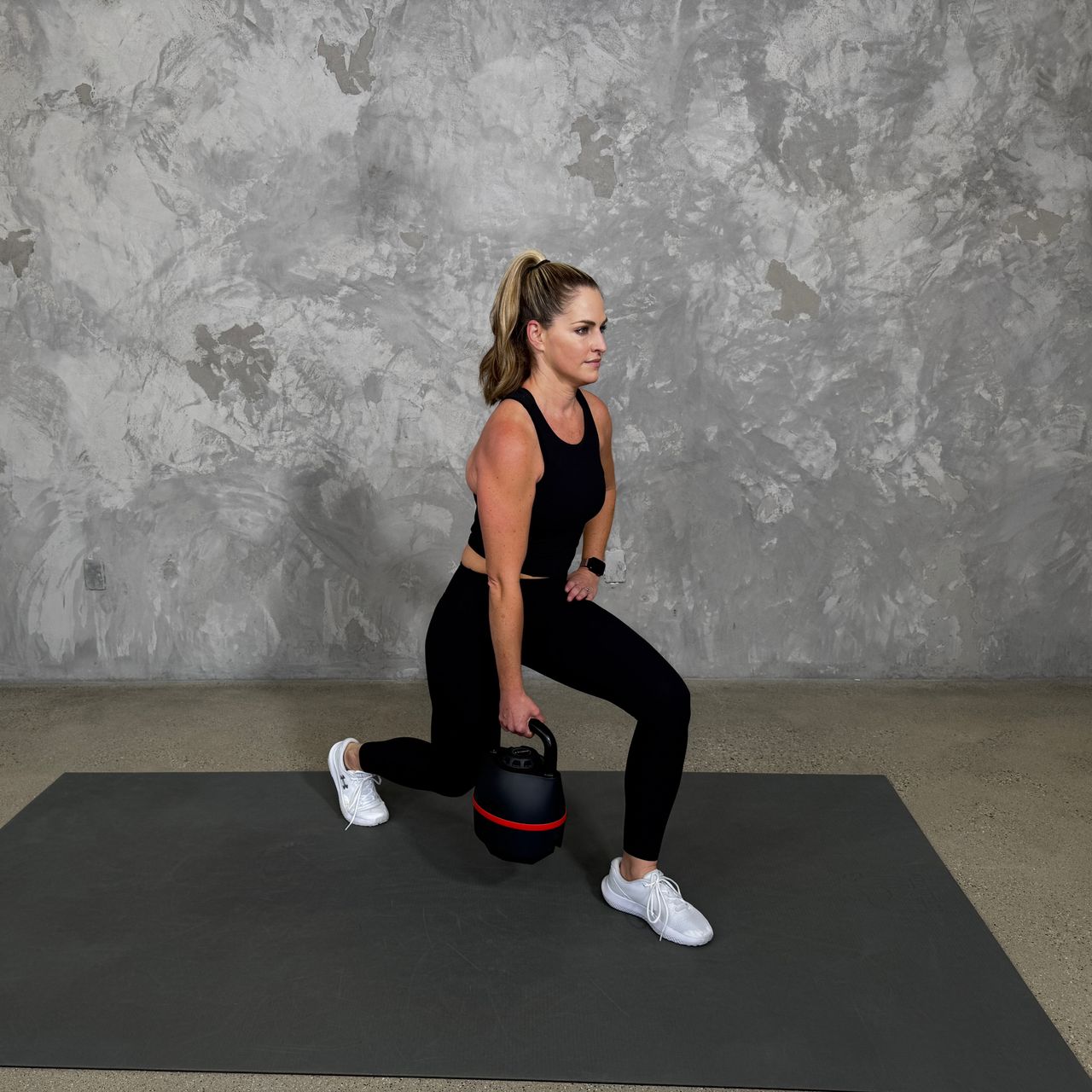 Woman in blue sportswear exercises with kettlebell