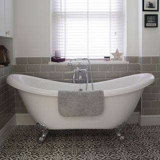 bathroom with bathtub white and grey brick wall window and white and black designed flooring
