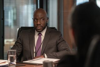 McKinley Belcher III as carl wearing a grey suit and purple tie at a desk in a still from zero day