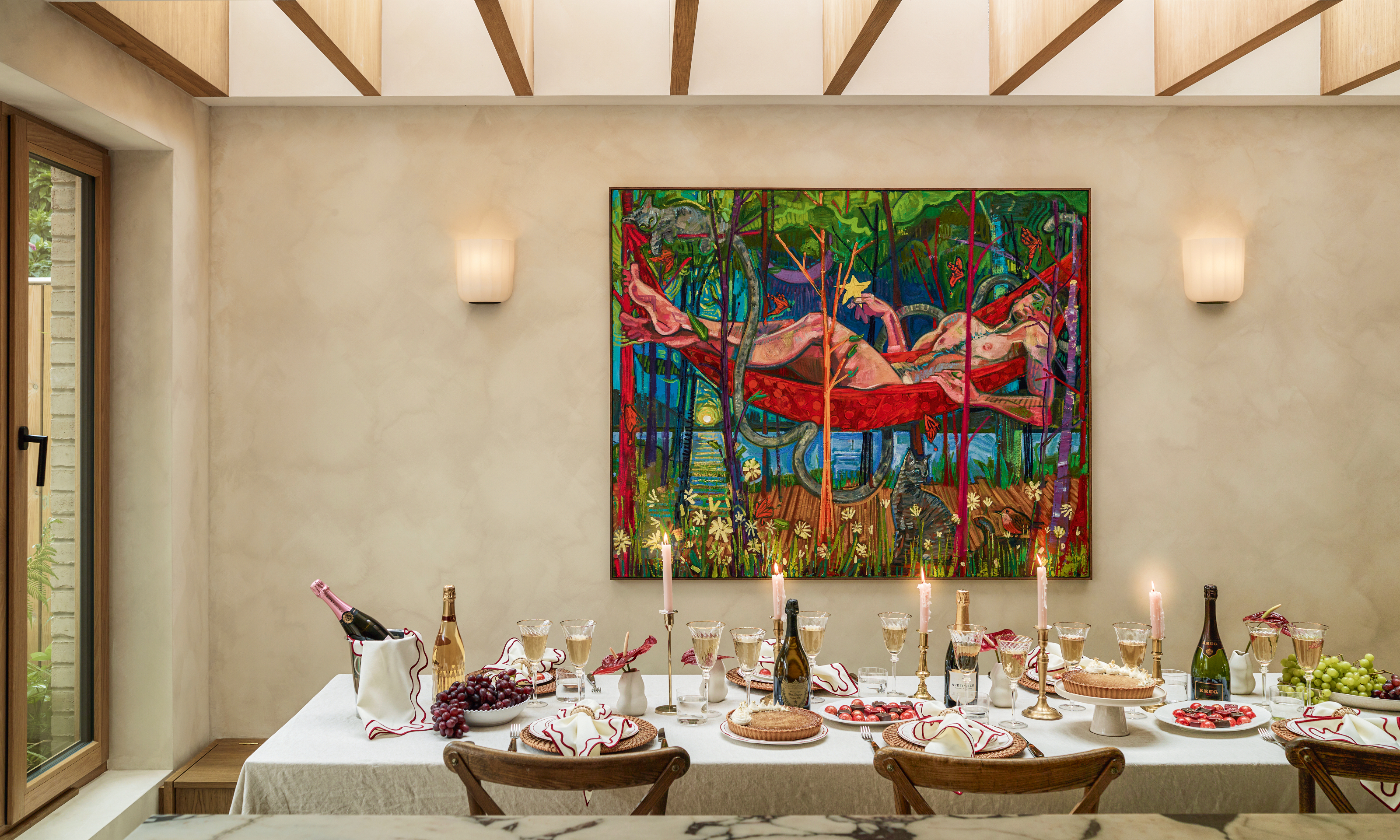 Table in extension dressed with candles for Christmas, with colorful art on the wall