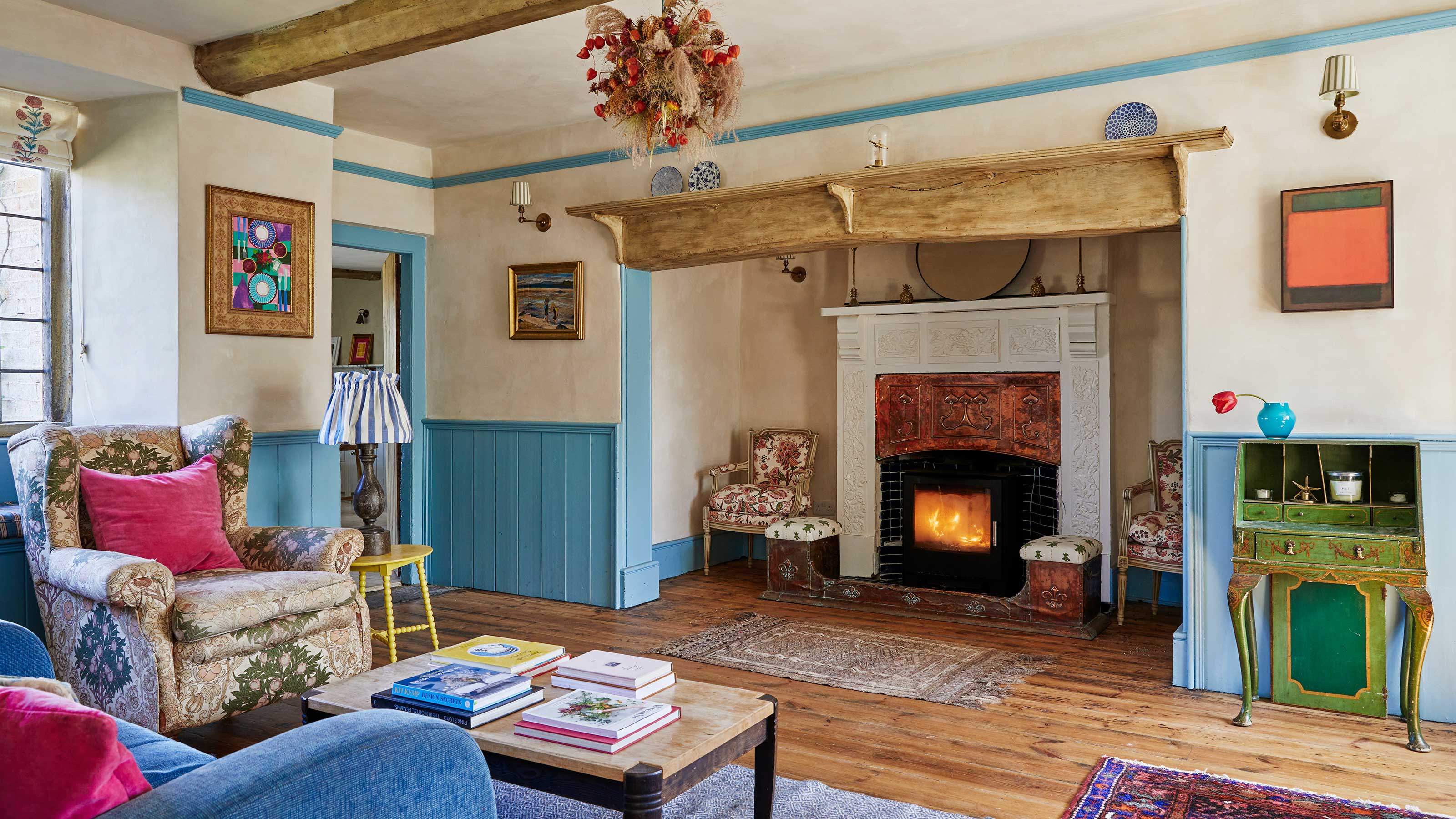 living room of country home with log burner in inglenook fireplace, blue painted woodwork and wooden floor