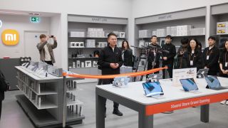 Xiaomi staff line up behind an orange ribbon at the opening of its London Stratford Westfield store