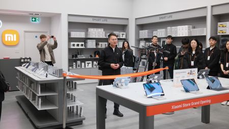 Xiaomi staff line up behind an orange ribbon at the opening of its London Stratford Westfield store