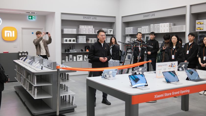 Xiaomi staff line up behind an orange ribbon at the opening of its London Stratford Westfield store
