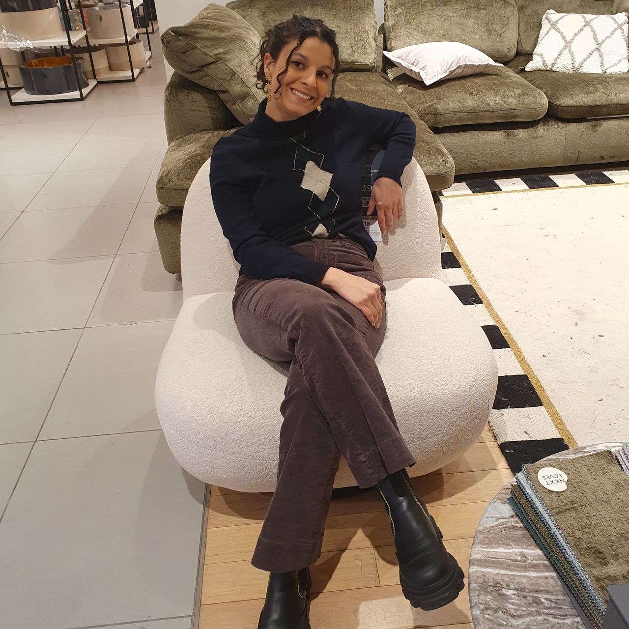 Sara sitting on the Otis swivel chair in a Next store