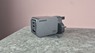 UGreen Nexode Pro 65W 3-Port Charger on stone surface against pink background