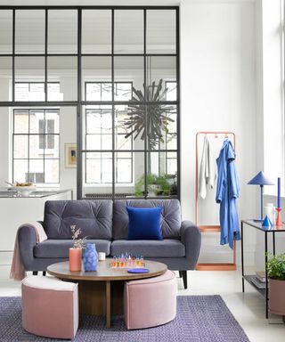 A living room with black Crittal-style windows with view of kitchen