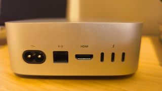 A silver Apple Mac mini (M4) on a wooden desk