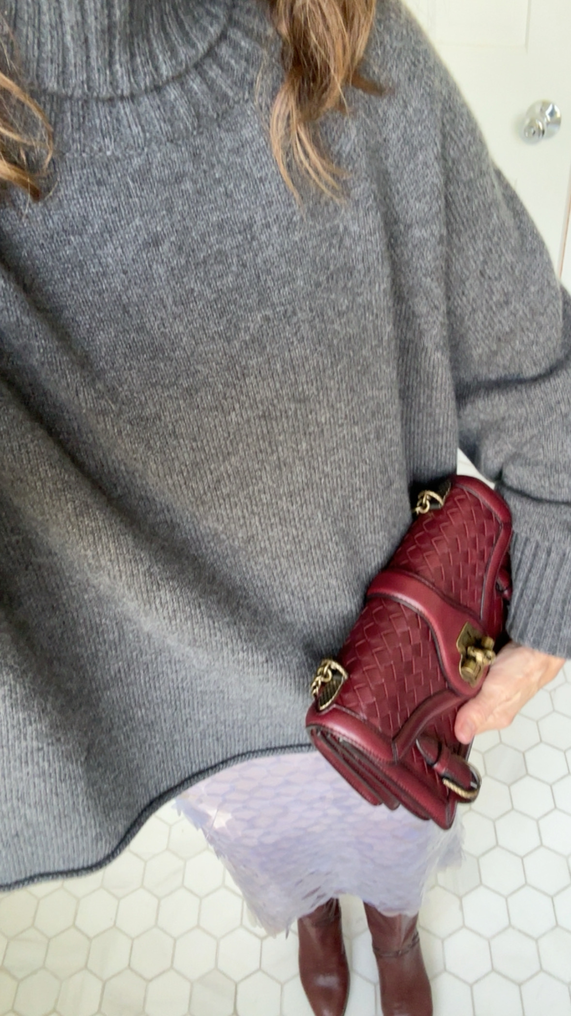 Larissa Mills with a vintage red designer bag and gray sweater