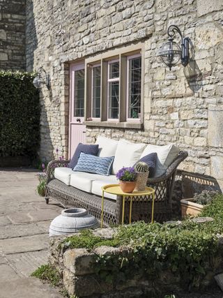 exterior of cottage with flagstone floors and rattan sofa